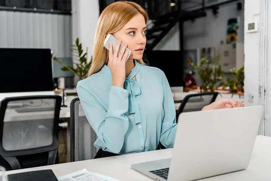 Procurement officer on a phone call while reviewing a supplier deal on her laptop